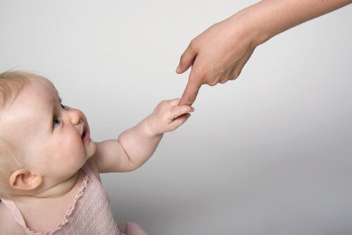 A baby holding an adult's hand.