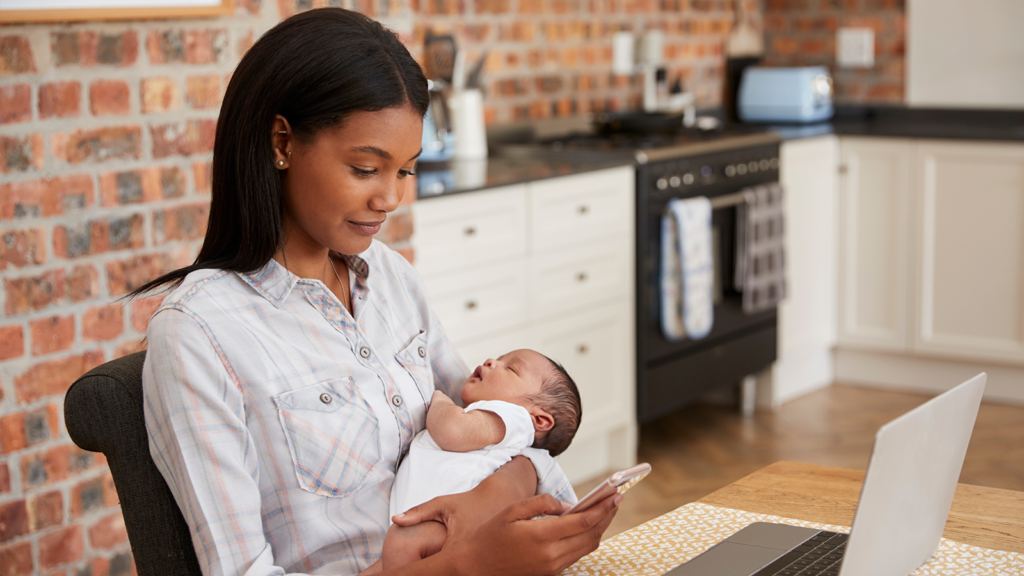 Black woman holding infant while working