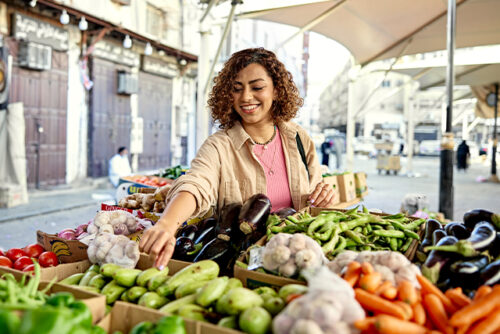 woman checking out produce at street market.