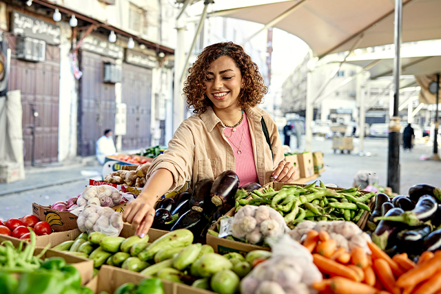 woman checking out produce at street market.